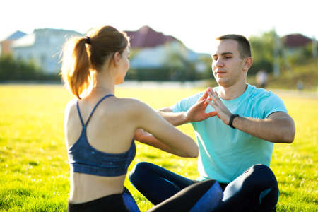 Young sportive couple doing yoga fitness exercises on warm summer day outdoors.の写真素材