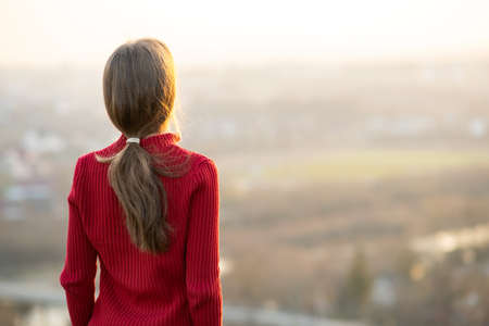 Young woman standing outdoors enjoying city view. Relaxing, freedom and wellness concept.