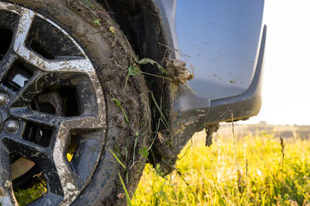 Close up of dirty off road car wheels with dirty tires covered with yellow mud.