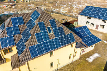 Aerial top view of new modern residential house cottage with blue shiny solar photo voltaic panels system on roof. Renewable ecological green energy production concept.のeditorial素材