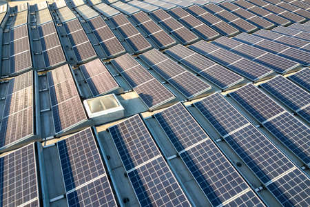 Aerial view of many photo voltaic solar panels mounted of industrial building roof.の写真素材