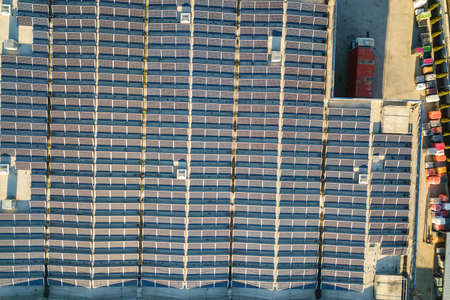Aerial view of many photo voltaic solar panels mounted of industrial building roof.