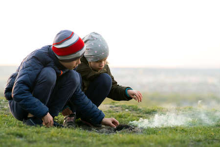 Two children playing with fire outdoors in cold weather.