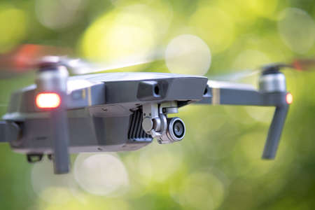 Drone copter with blurred propellers and video camera flying in air.