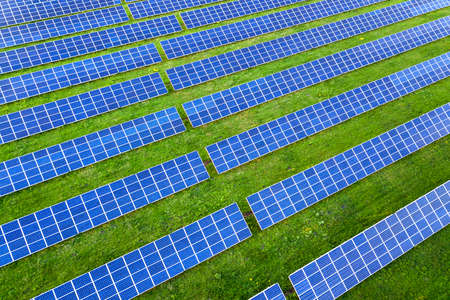 Surface of solar photo voltaic panels system producing renewable clean energy on green grass background.の写真素材