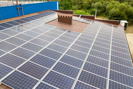 Aerial view of solar power plant with blue photovoltaic panels mounted of industrial building roof.