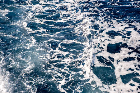 Top down aerial view of sea water surface. White foam waves texture as natural background.