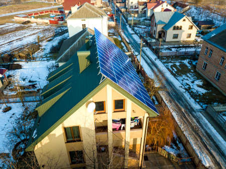 Aerial view of new modern two story house cottage with blue shiny solar photo voltaic panels system on the roof. Renewable ecological green energy production concept.のeditorial素材