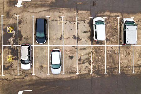 Top down aerial view of many cars on a parking lot of supermarket or on sale car dealer market.