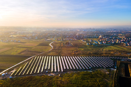 Aerial view of solar power plant under construction on green field. Assembling of electric panels...