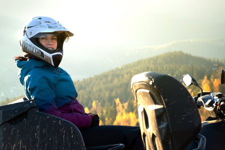 Happy woman driver in protective helmet enjoying extreme riding on ATV quad motorbike in summer...