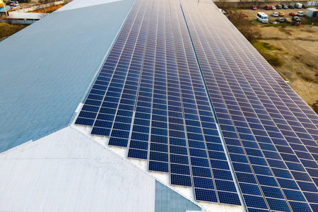 Aerial view of surface of blue photovoltaic solar panels mounted on building roof for producing...