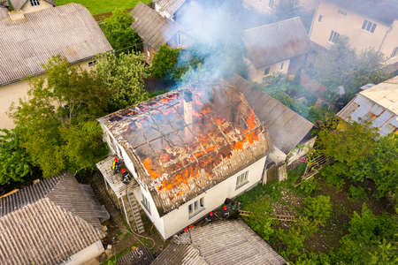 Aerial view of a house on fire with orange flames and white thick smoke.の写真素材