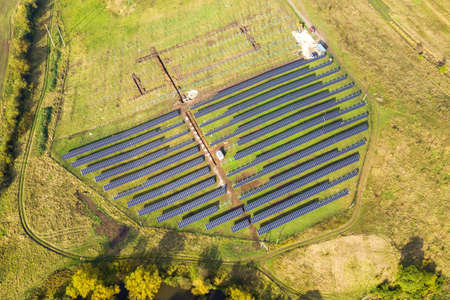 Aerial view of solar power plant under construction on green field. Assembling of electric panels...