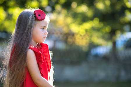 Portrait of pretty fashionable child girl in red dress enjoying warm sunny summer day.の写真素材