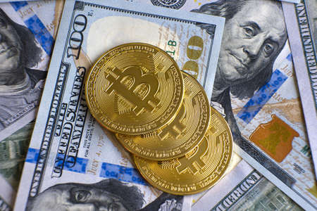 Close up of metal shiny bitcoin crypto currency coins on US dollar bills. Electronic decentralized...