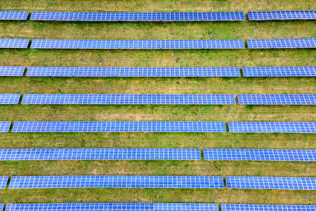 Aerial view of solar power plant on green field. Electric farm with panels for producing clean ecologic energy.の写真素材