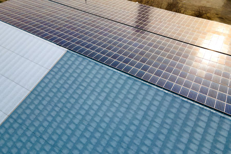 Aerial view of surface of blue photovoltaic solar panels mounted on building roof for producing...