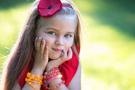 Portrait of happy beautiful child girl outdoors enjoying warm sunny summer day.の写真素材