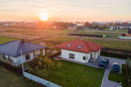 Aerial view of a private suburban house with parked cars in back yard.