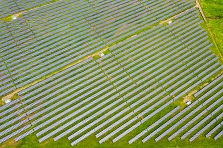 Aerial view of solar power plant on green field. Electric panels for producing clean ecologic...
