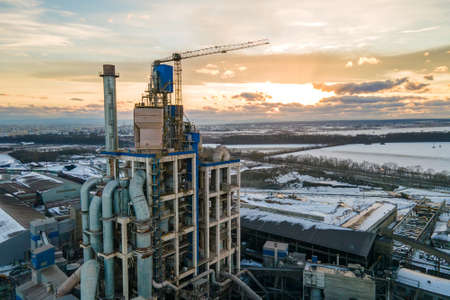 Aerial view of cement plant with high factory structure and tower crane at industrial production area at sunset.の写真素材