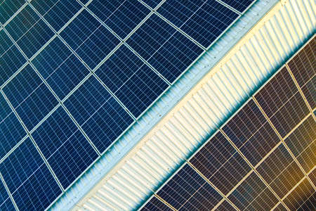 Aerial view of surface of blue photovoltaic solar panels mounted on building roof for producing...