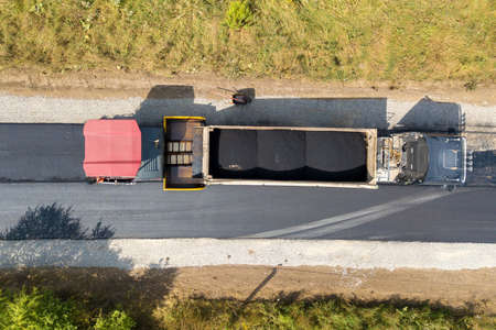 Aerial view of new road construction with asphalt laying machinery at work.