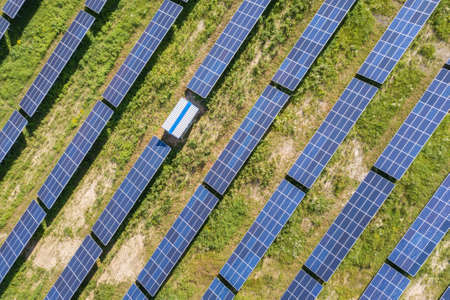Aerial view of solar power plant on green field. Electric farm with panels for producing clean...