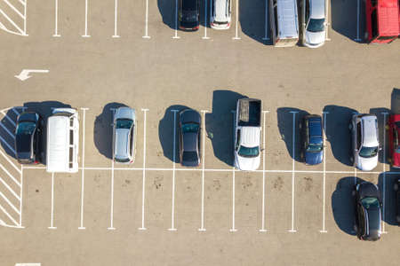 Aerial view of many colorful cars parked on parking lot with lines and markings for parking places...