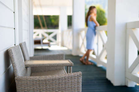 Blurred view of woman in blue dress standing on balcony and looking on nature. Concept of enjoying fresh air and nature.の写真素材