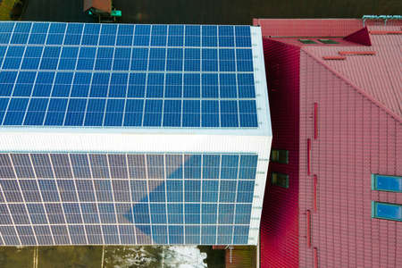 Aerial view of surface of blue photovoltaic solar panels mounted on building roof for producing...