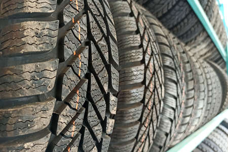 Many black rubber car tires on store shelf for sale.