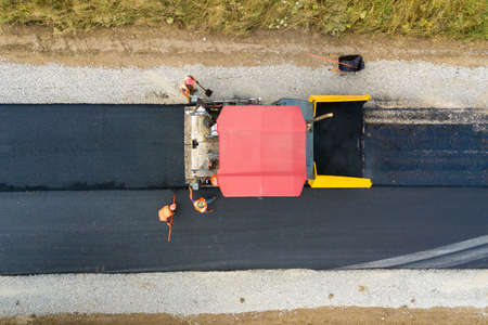 Aerial view of new road construction with asphalt laying machinery at work.