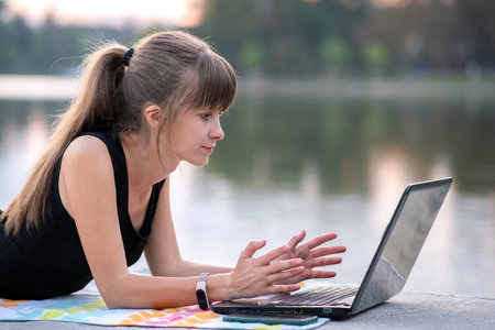 Exhausted young woman working behind laptop computer lying down in summer park outdoors. Problems...