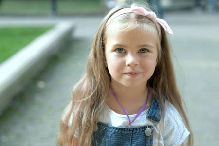 Portrait of pretty child girl standing outdoors in summer park.