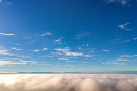 Aerial view from above of white puffy clouds in bright sunny day.