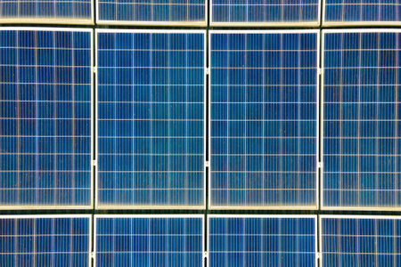 Aerial view of surface of blue photovoltaic solar panels mounted on building roof for producing...