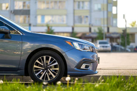 Car parked on a city street side with blurred urban traffic.の写真素材