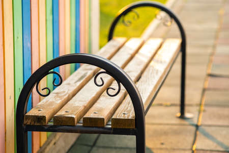 Closeup of wooden park bench with metal handgrip outdoors.の写真素材