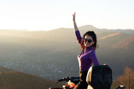 Happy active female driver enjoying extreme riding on ATV quad motorbike in fall mountains at sunset.の写真素材