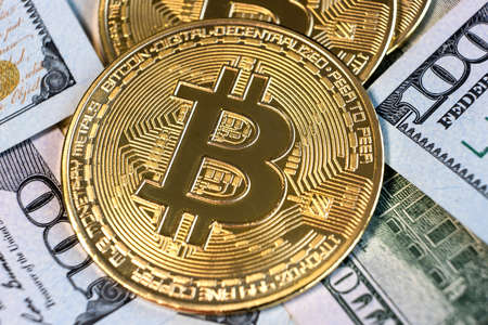 Close up of metal shiny bitcoin crypto currency coin on US dollar bills. Electronic decentralized...