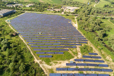 Aerial view of solar power plant on green field. Electric farm with panels for producing clean...