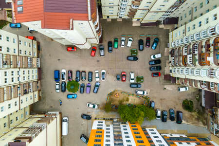 Aerial view of parked cars on parking lot between high apartment buildings.