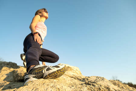 Woman hiker climbing steep big rock on a sunny day. Young female climber overcomes difficult climbing route. Active recreation in nature concept.の写真素材