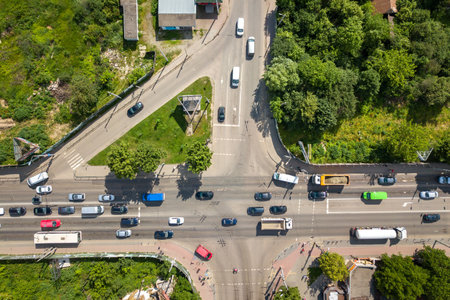 Top down aerial view of busy street intersection with moving cars traffic.