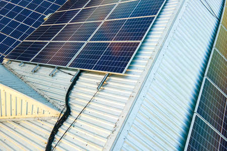 Aerial view of surface of blue photovoltaic solar panels mounted on building roof for producing...