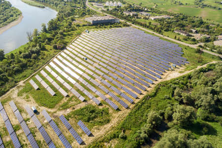 Aerial view of solar power plant on green field. Electric farm with panels for producing clean...