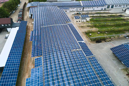 Aerial view of solar power plant with blue photovoltaic panels mounted on industrial building roof...