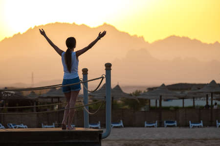 Happy woman relaxing outdoors on hotel deck on sea shore enjoying warm tropic evening. Summer vacations and traveling concept.の写真素材